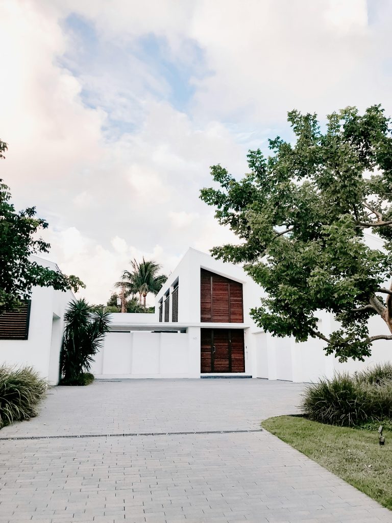 Contemporary minimalist home exterior with lush landscaping and open driveway.